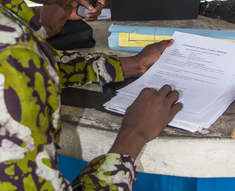 Un formateur relit ses documents avant son cours, son téléphone à la main