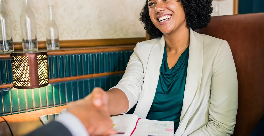Une formatrice souriante accueille une personne à sa table